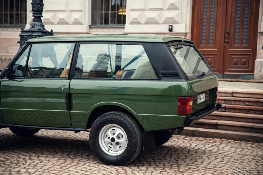 Vintage green SUV parked near building entrance.