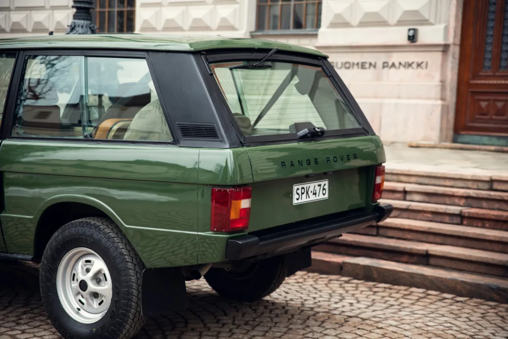 Vintage green Range Rover parked near building.