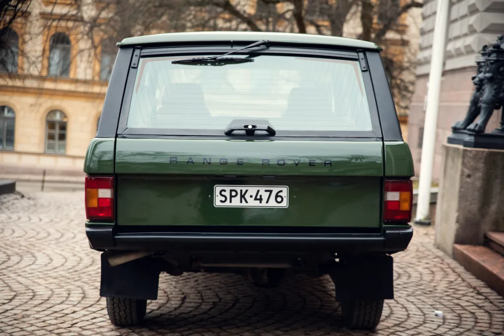 Green Range Rover rear view on cobblestone street.