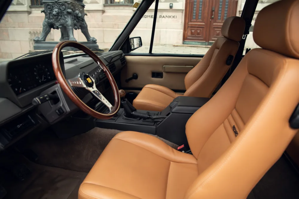 Vintage car interior, leather seats, wooden steering wheel.