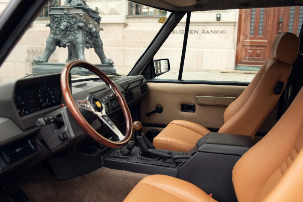Vintage car interior with leather seats and wooden steering wheel.