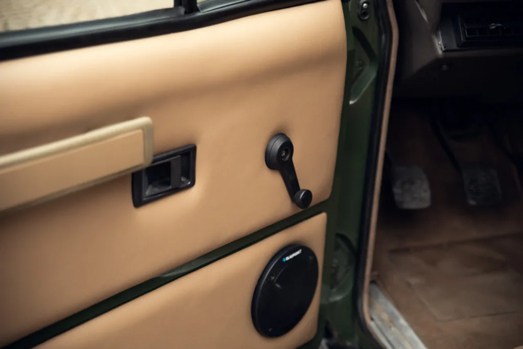 Vintage car interior with manual window crank.