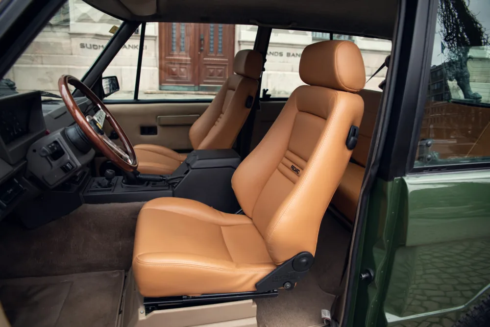 Tan leather car seats with wooden steering wheel.