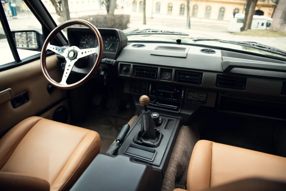 Vintage car interior with leather seats and manual transmission.