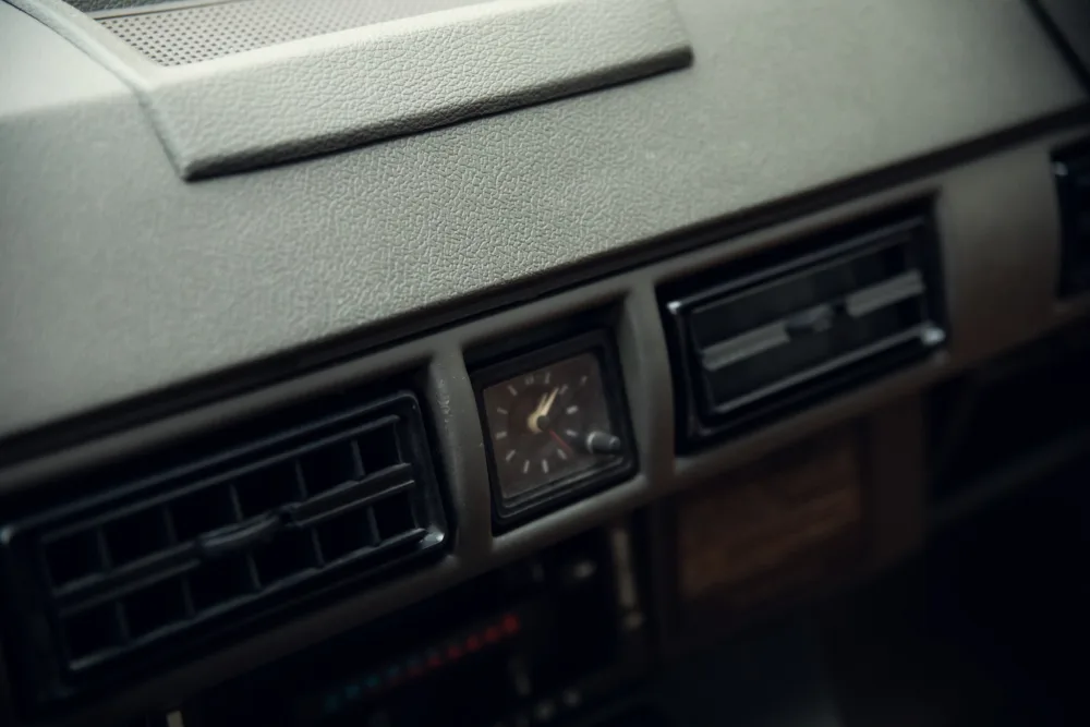 Vintage car dashboard with analog clock and air vents.