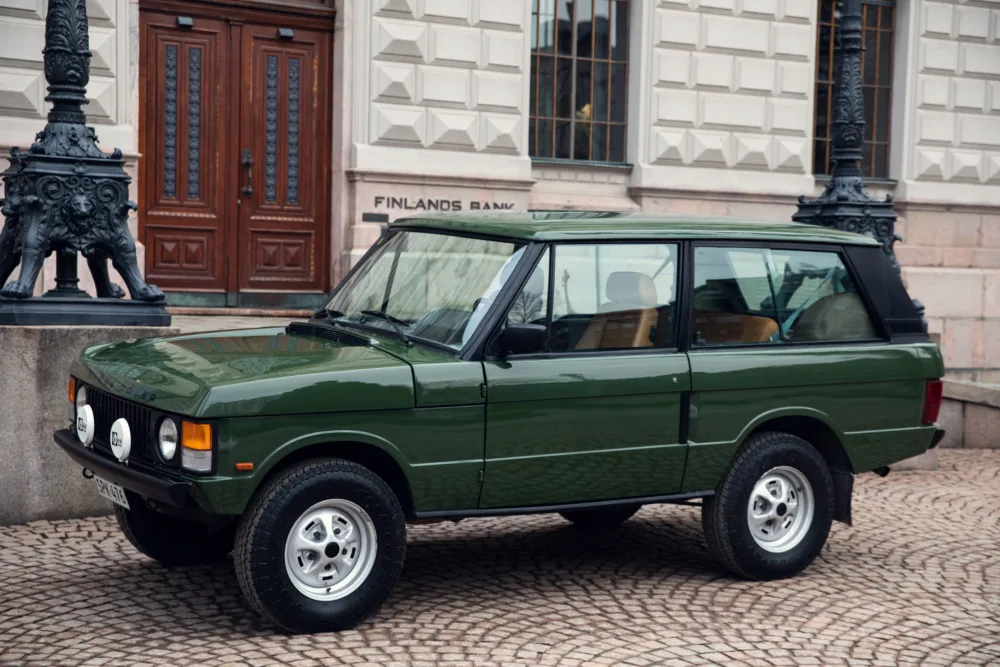 Vintage green SUV parked outside historic building.