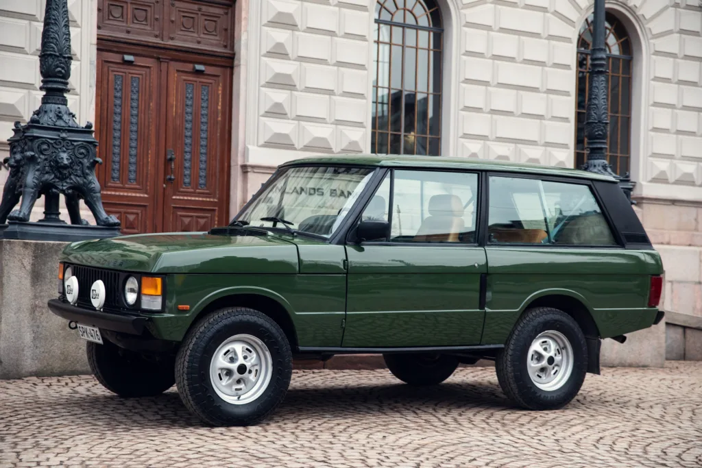 Vintage green SUV parked near historic building.