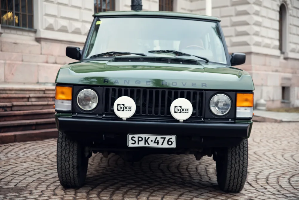 Vintage green Range Rover classic on cobblestone street.