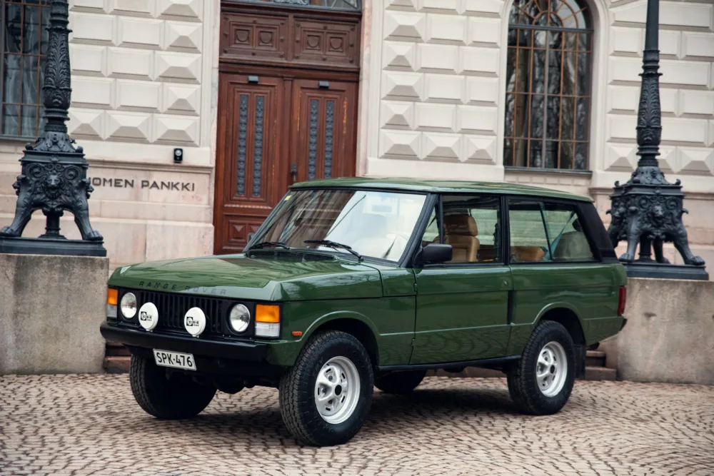 Vintage green Range Rover parked in urban area.
