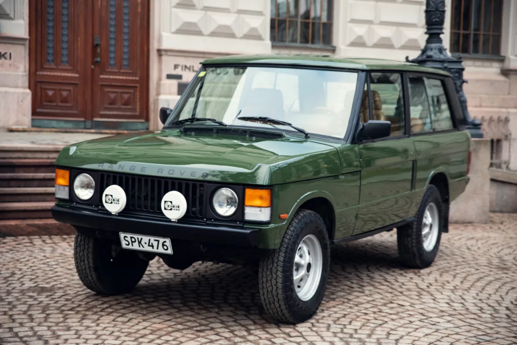 Vintage green Range Rover parked on cobblestone street.