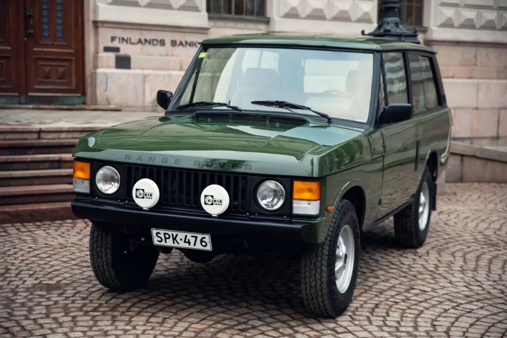 Vintage green Range Rover parked on cobblestone street.