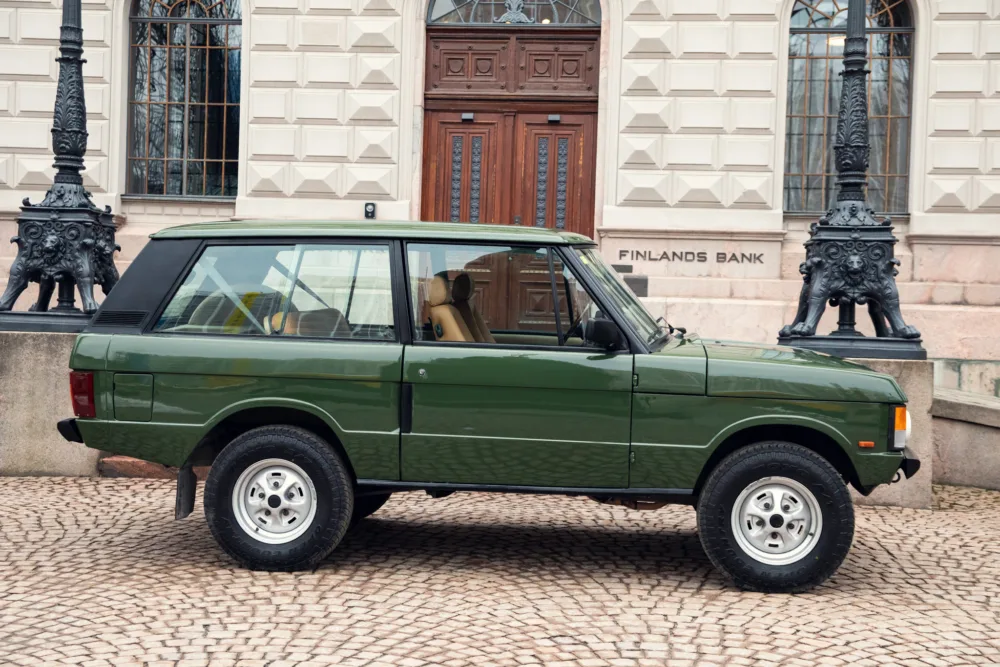 Green vintage SUV parked near historic bank building