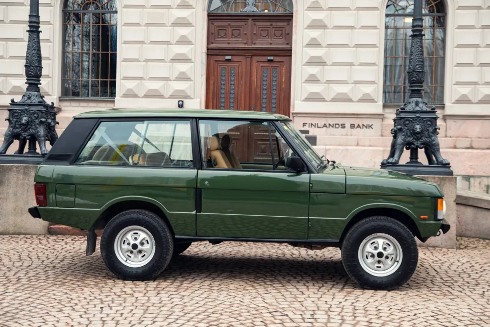 Green SUV parked outside historic building.