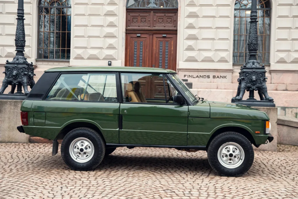 Vintage green SUV parked near historical building.