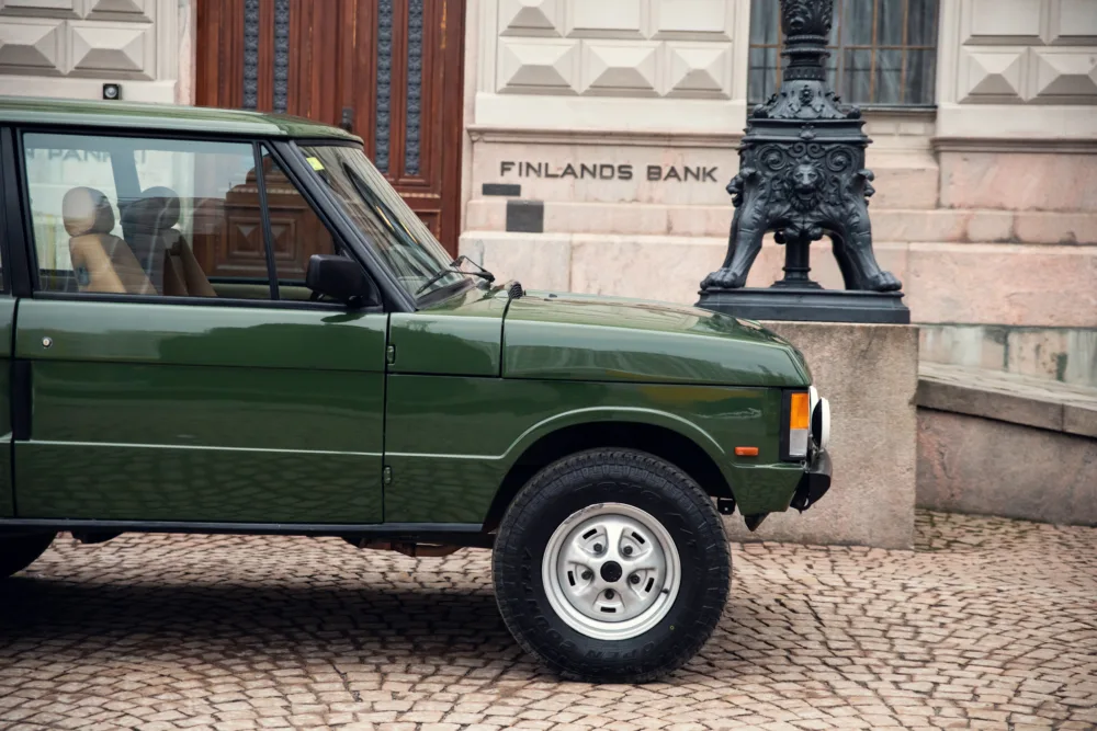 Green SUV parked near historic building.