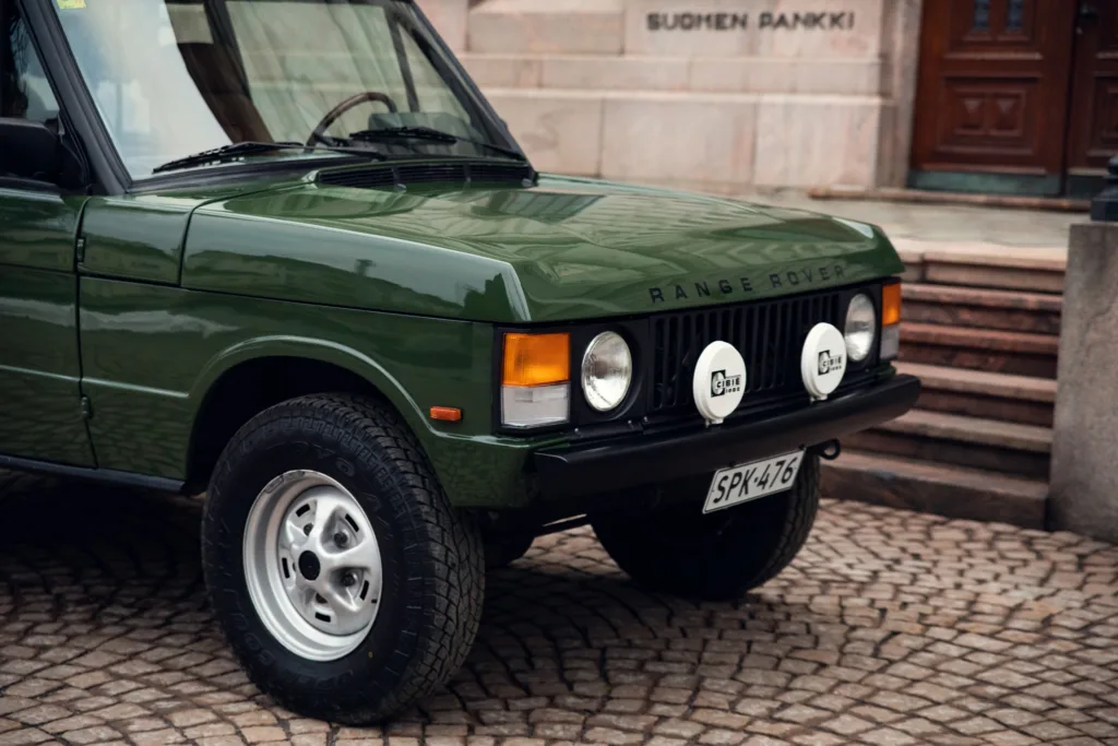 Vintage green Range Rover parked on cobblestone street.
