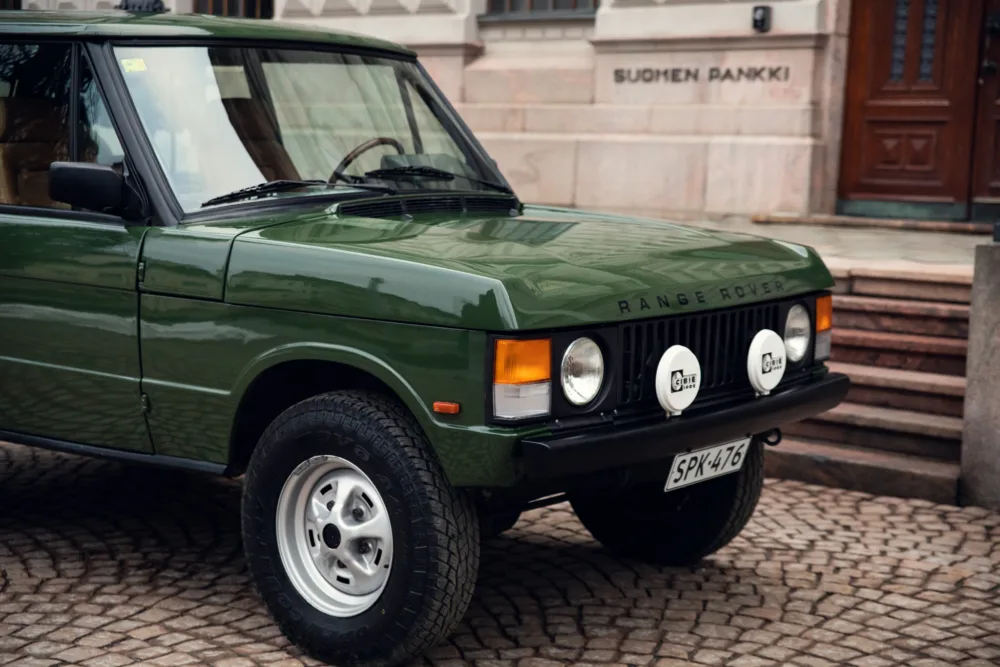 Green Range Rover classic parked in urban setting.