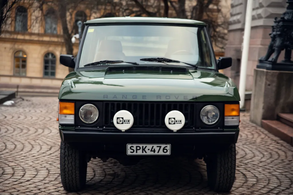 Vintage green Range Rover parked on cobblestone street.