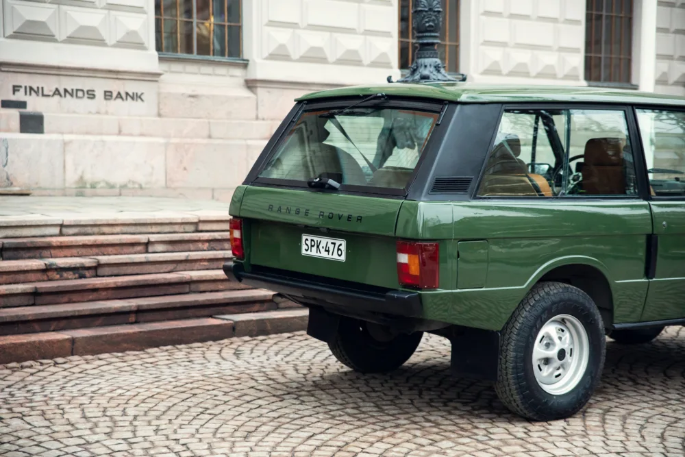 Vintage green Range Rover parked by stone steps.
