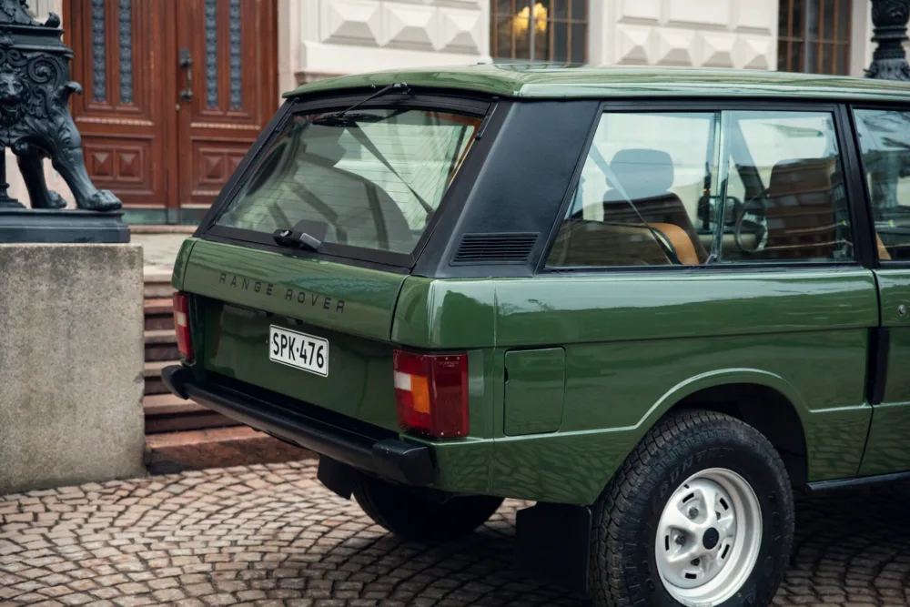 Green Range Rover classic parked outside building.