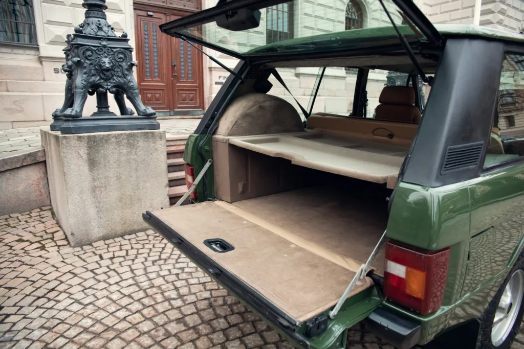 Vintage car hatchback open on cobblestone street.
