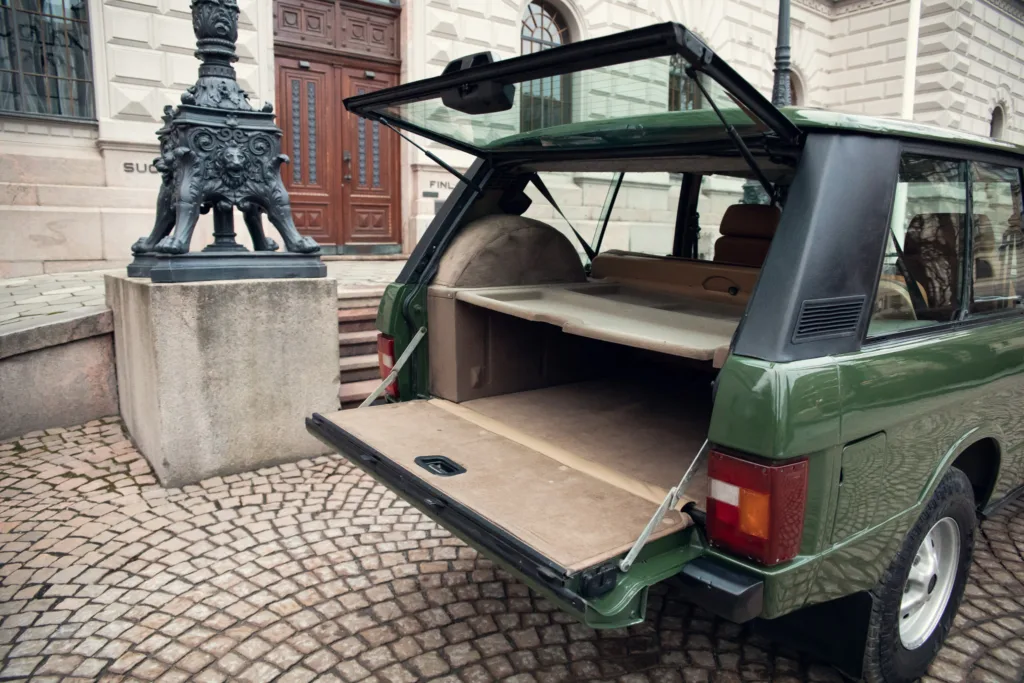 Green vintage car with open trunk city street