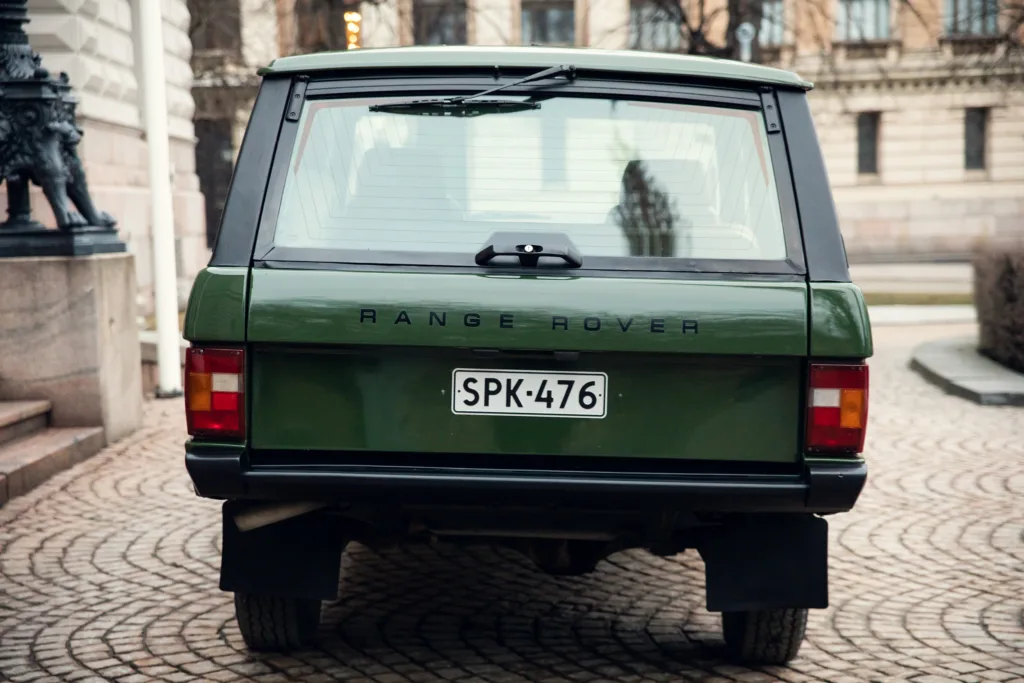 Green Range Rover rear view on cobblestone street.
