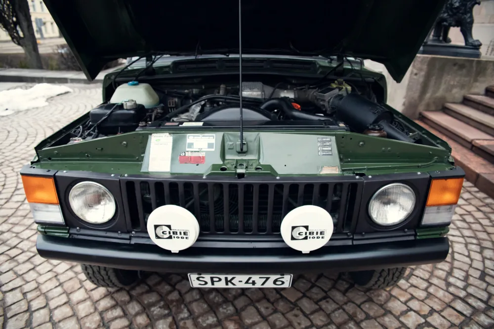 Green classic SUV with open hood showing engine