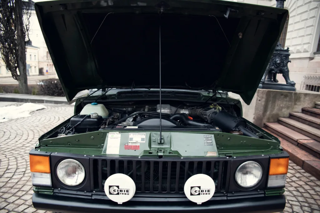 Green vintage car with open hood.