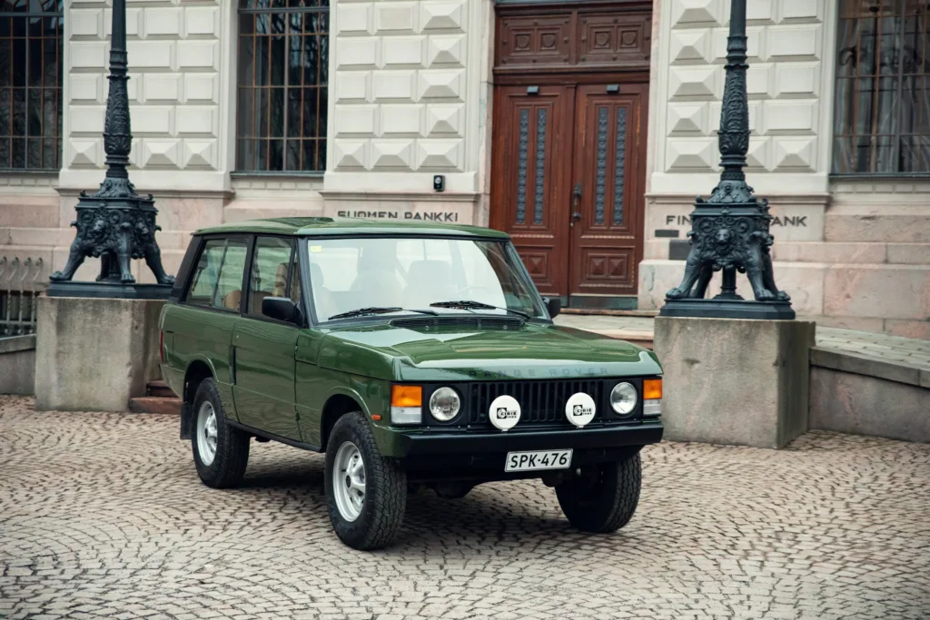 Vintage green Range Rover parked on cobblestone street.