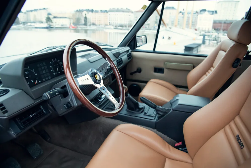 Vintage car interior with leather seats and wooden steering wheel.
