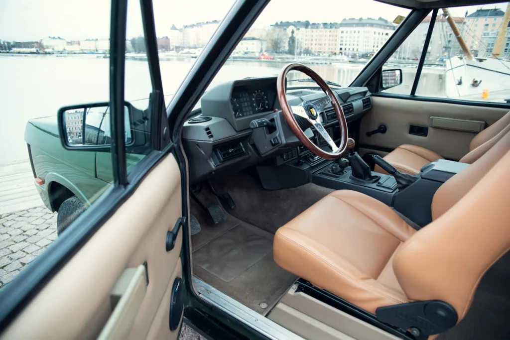 Vintage car interior with leather seats and wooden steering wheel.