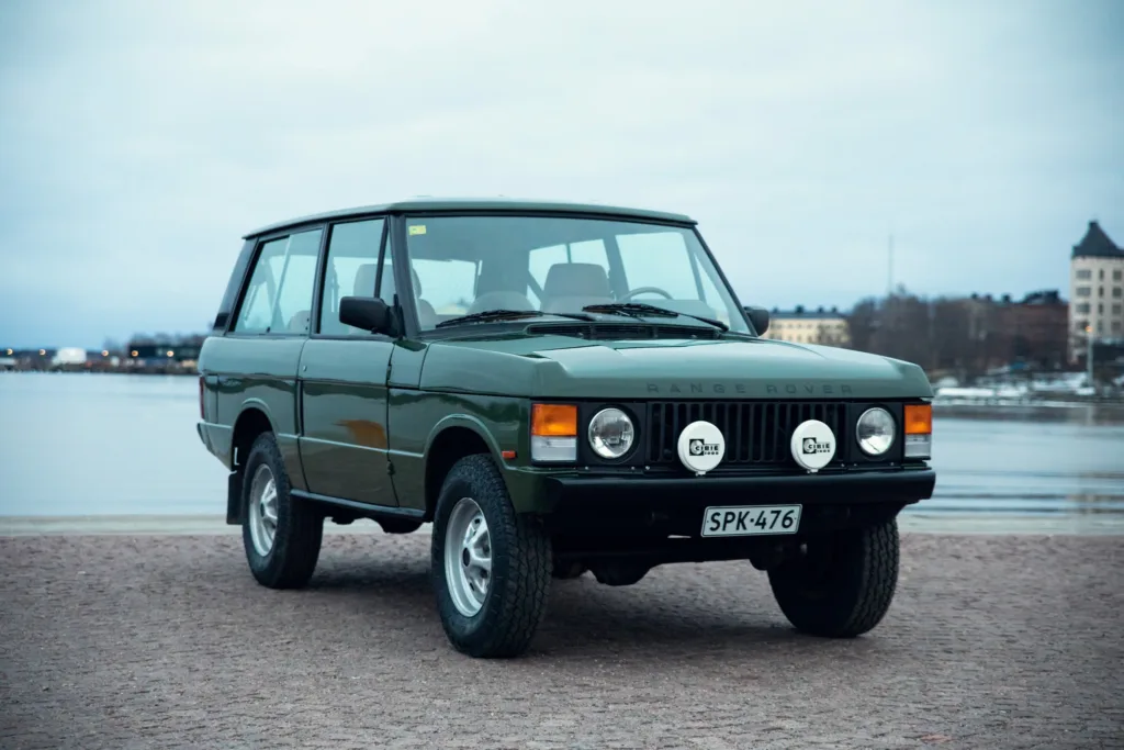 Vintage Range Rover parked by water.