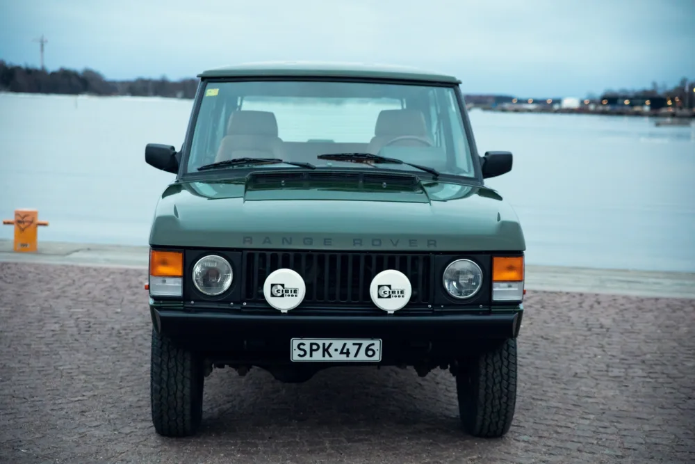 Vintage Range Rover parked by lakeside at twilight.