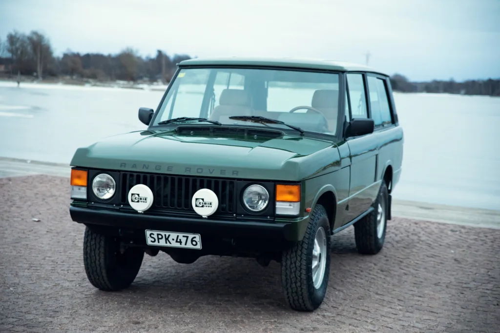 Vintage Range Rover parked by frozen lake.