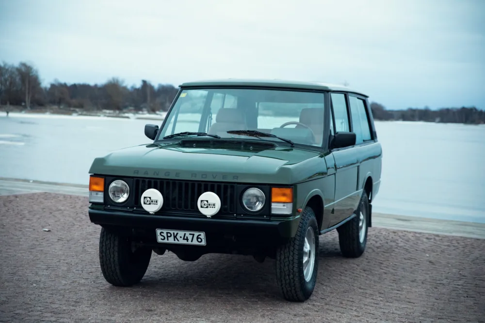 Vintage Range Rover parked by a frozen lake.