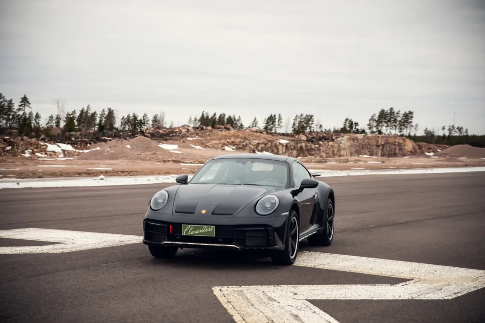 Black sports car on empty road with snowy landscape
