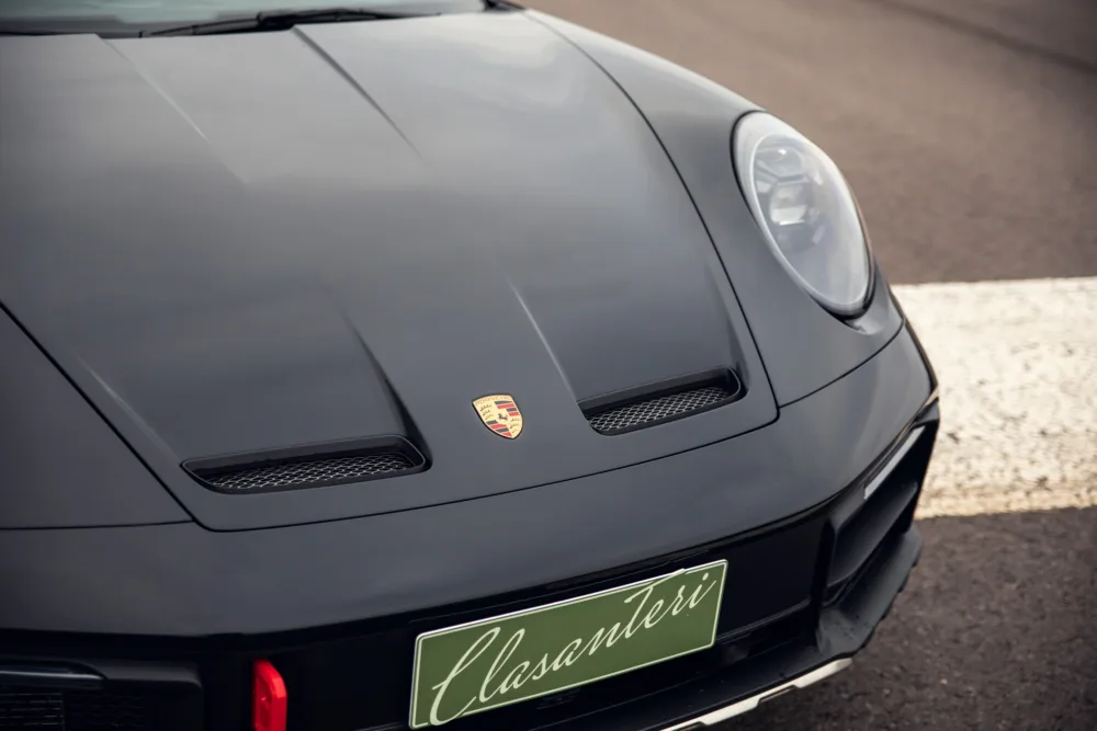 Black Porsche sports car front view with emblem.