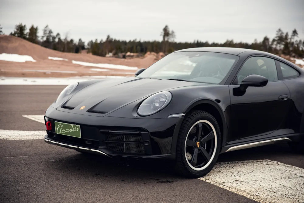 Black Porsche car parked on an asphalt road.