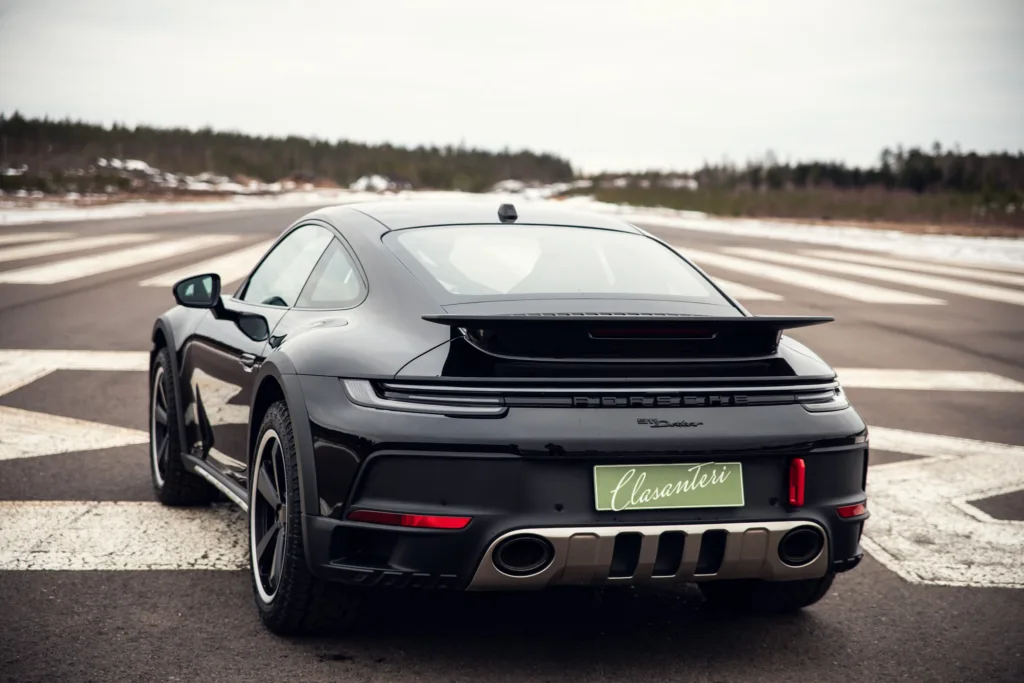 Black Porsche 911 on racetrack, rear view.