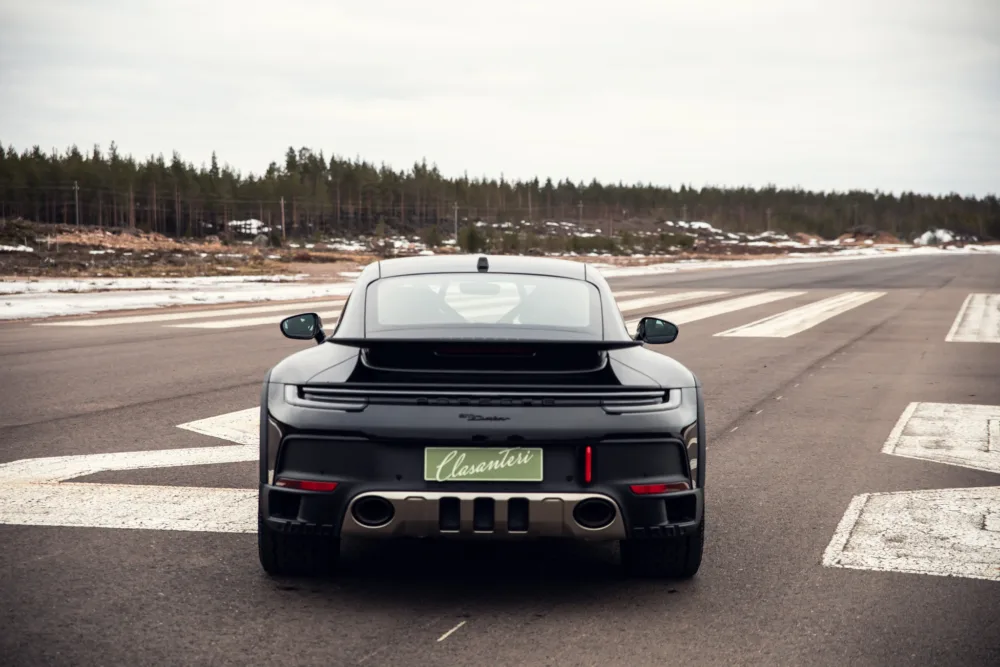Black sports car on empty road with trees