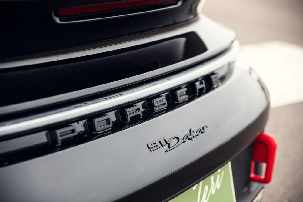 Close-up of Porsche car emblem and model badge.