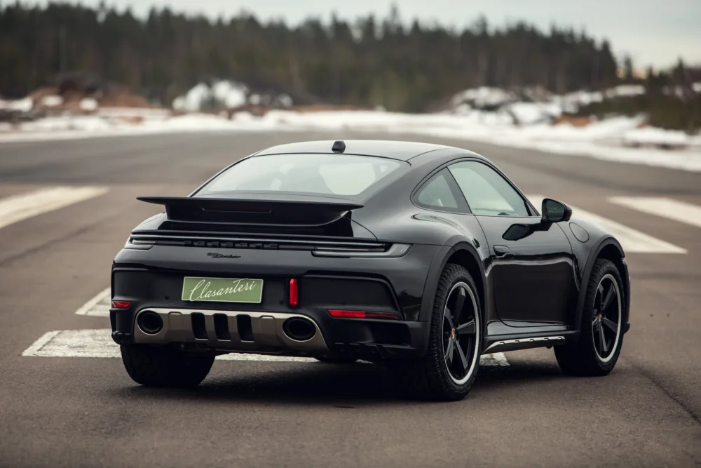 Black Porsche 911 Turbo on road with snowy background.