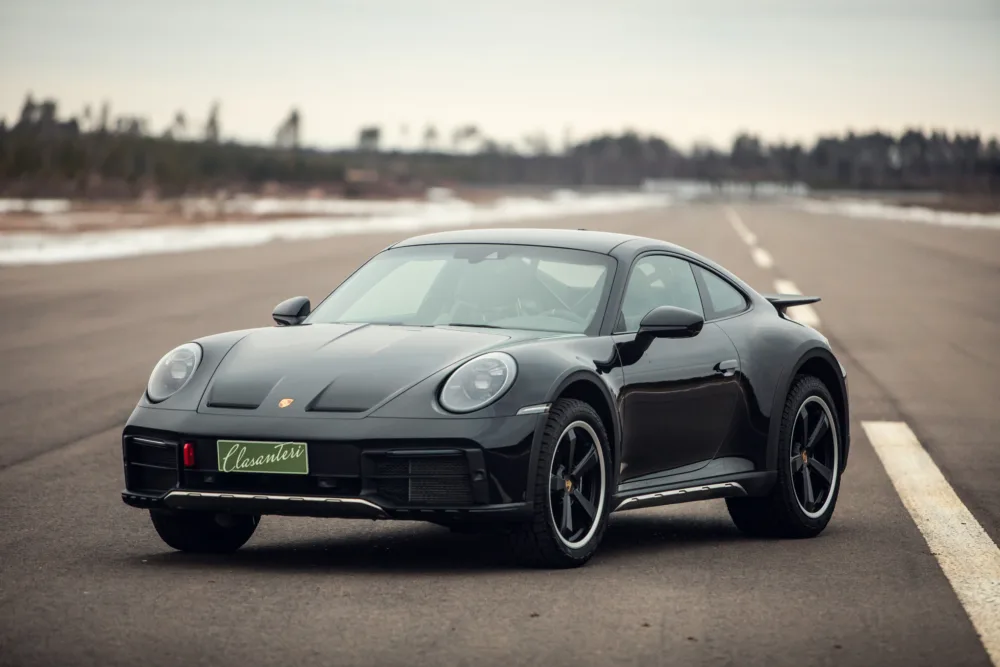 Black Porsche 911 on tarmac, winter setting.