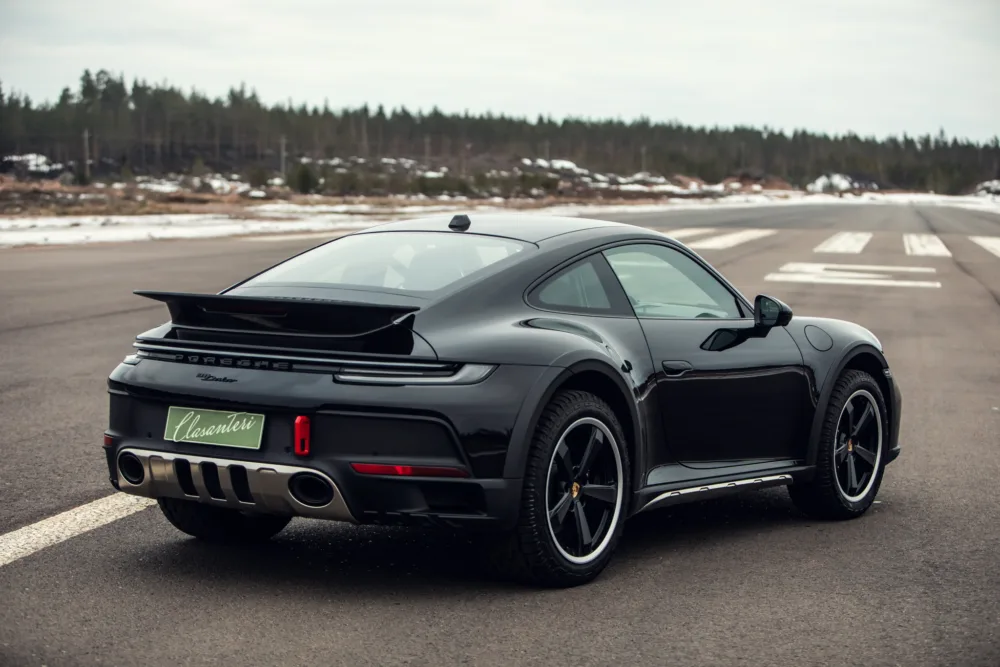 Black sports car parked on airstrip roadway.