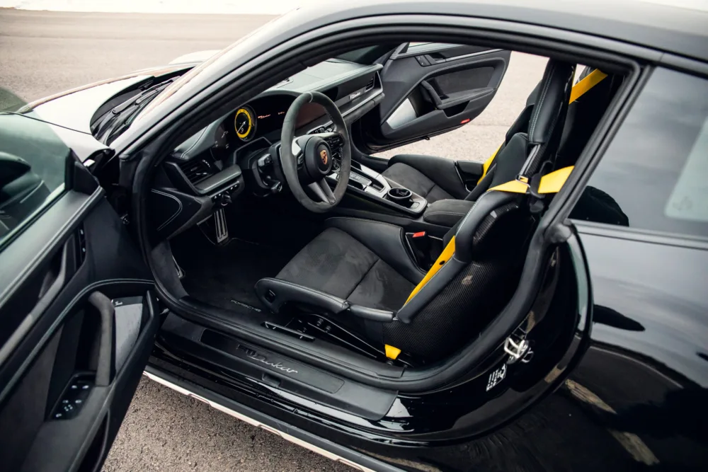 Black sports car interior, yellow seatbelts, luxury design.