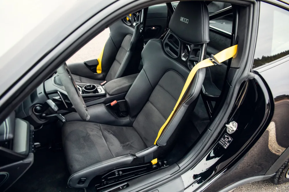 Sporty car interior with bucket seats and yellow seatbelts.