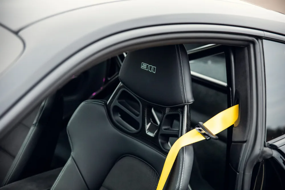 Sporty car interior with yellow seatbelt and logo.