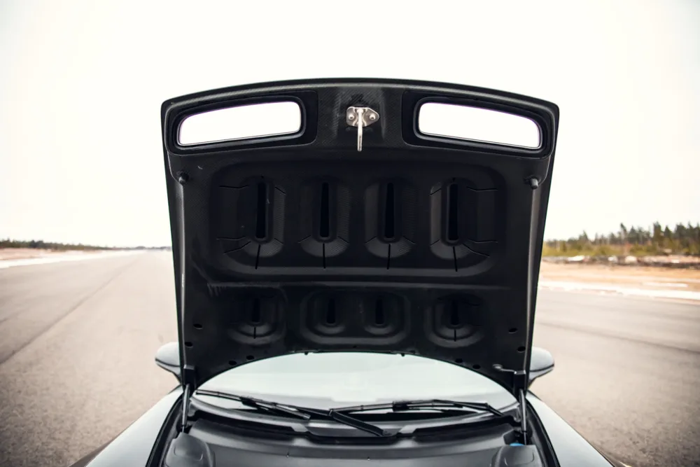 Open car hood showing engine bay on road.