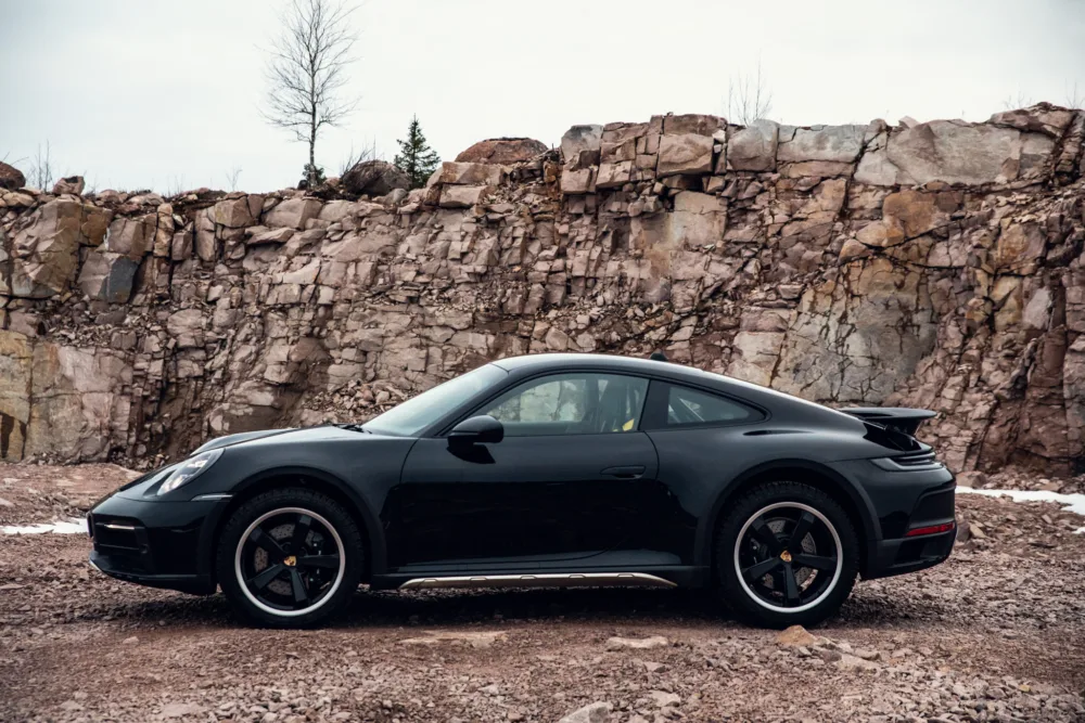 Black sports car parked in front of a rocky cliff